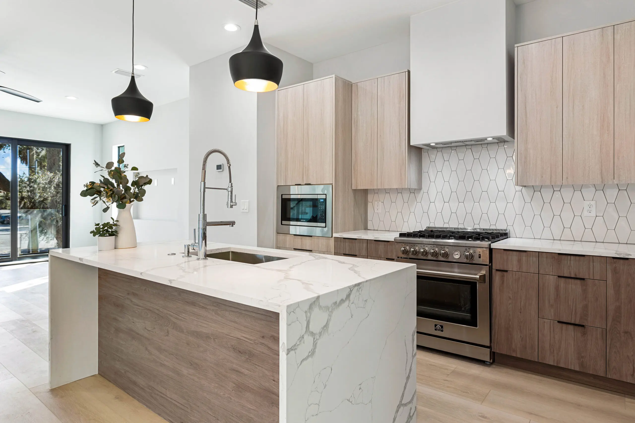 A kitchen with a sink, oven and microwave.